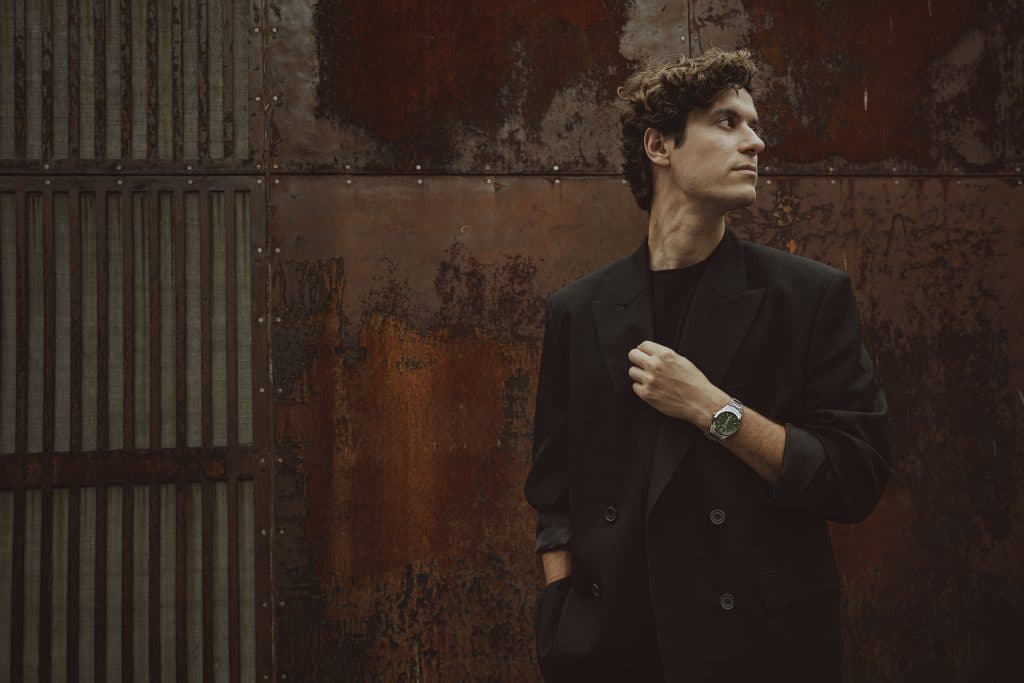 Casio edifice med grønn skive på arm foran murvegg