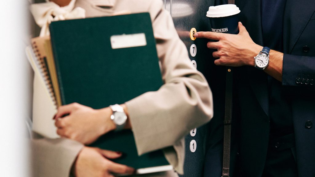 To personer i heis med Longines-klokker